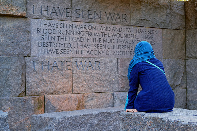 A woman in a head scarf pauses in front of a quote at the Franklin Delano Roosevelt Memorial. "I have seen war. I hate war."