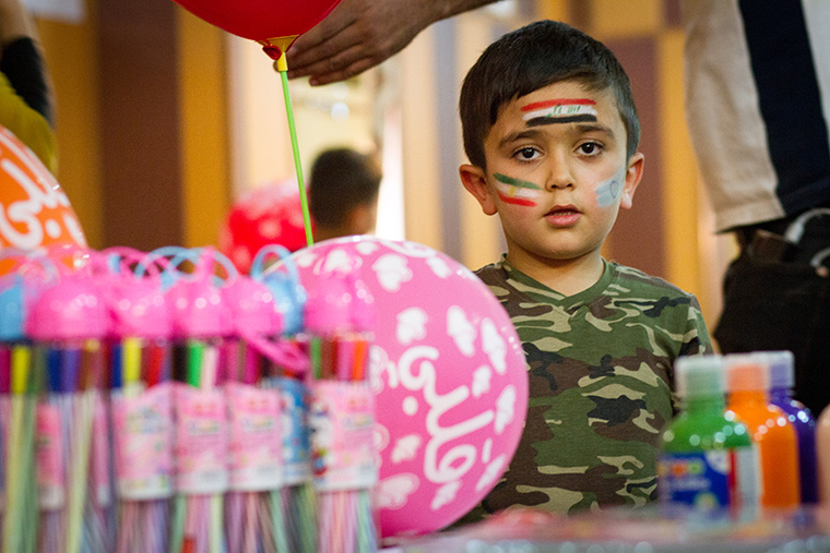 A young boy attends an Easter party, hosted by a local Assyrian community, dressed in military fatigues.