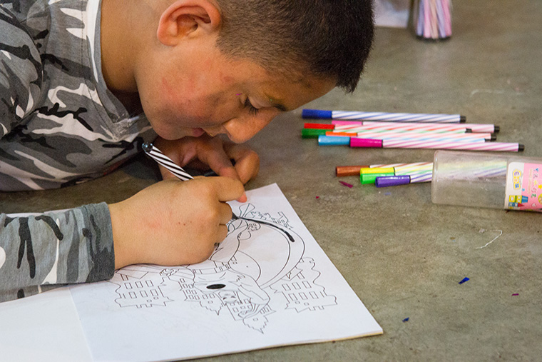 A young boy colours a superhero while attending an Easter party sponsored by a local Assyrian church.