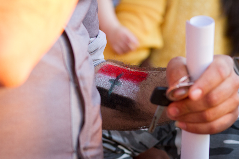 A parent made use of the face paint station to mark his forearm with a flag of his own making, featuring a cross at it's center.