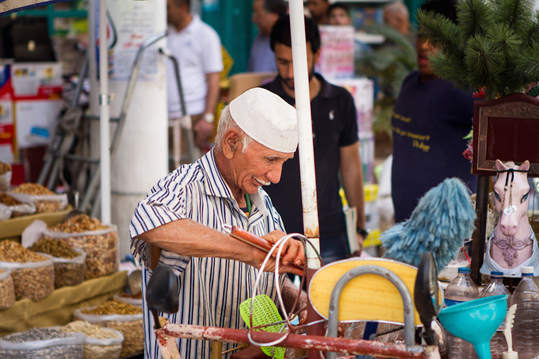 A vendor with a thin, white moustache prepares his wares.