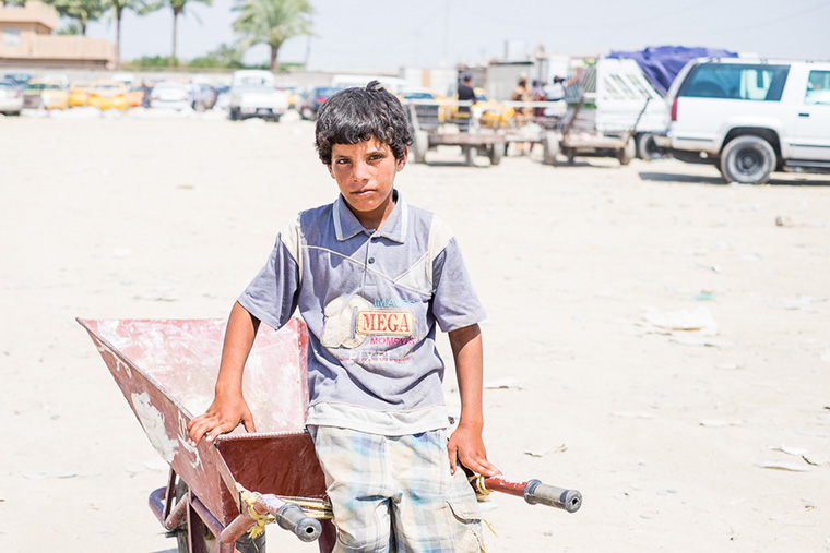 Not so much a teenager anymore–more a man–he works in the heat hauling supplies to displaced families from Ramadi with his wheelbarrow.