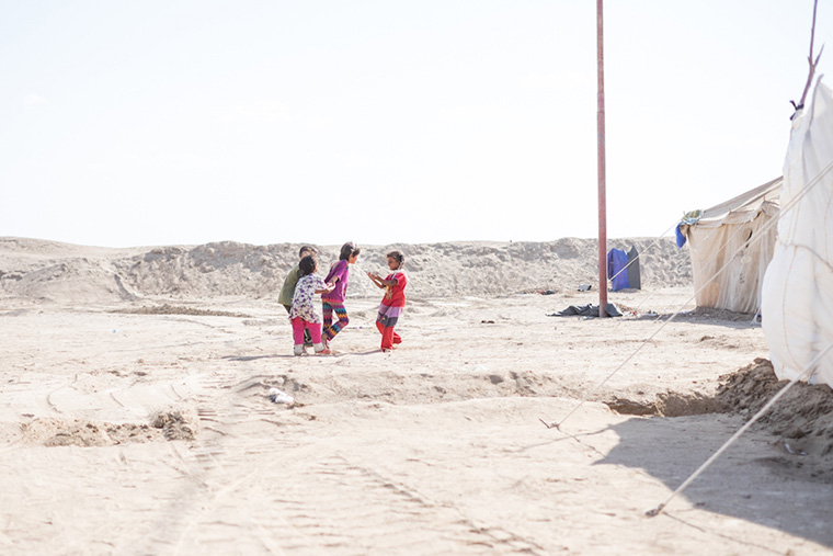Children play in the desert, beside their temporary tent-homes, after being displaced by ISIS in Iraq.