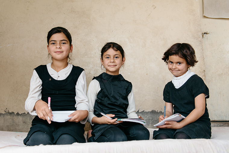 Young girls displaced by ISIS work on their homework after class.