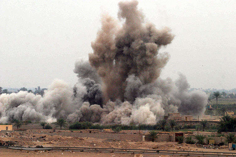 A cloud of dirt flies through the air, propelled by an explosion in Fallujah, Iraq.