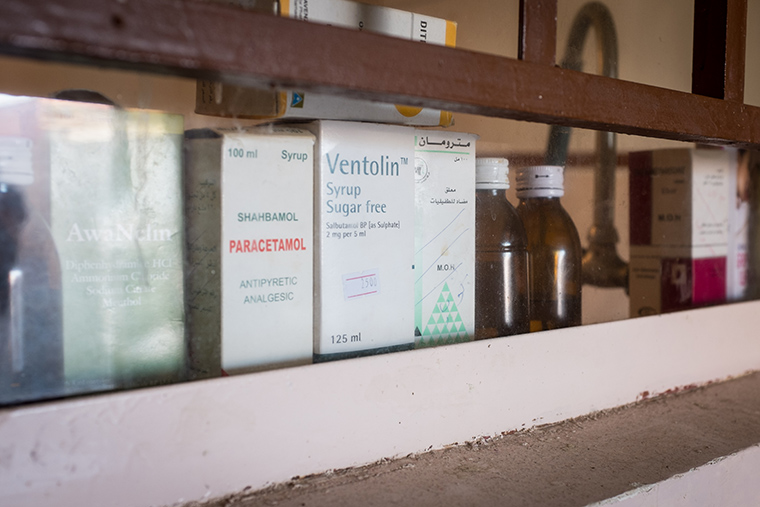 A row of cough syrup and medicine lines a window sill in an IDP house.
