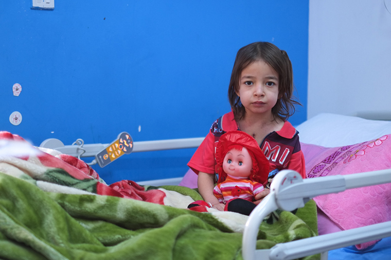 A young girl, Fatima, sits on her hospital bed in the city of Nasiriyah, Iraq.