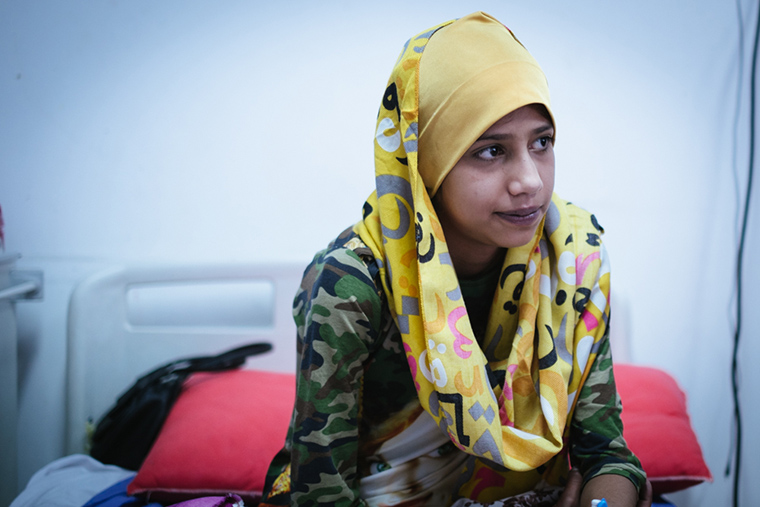 Saaja, sitting on her hospital bed, has been waiting 14 years for lifesaving heart surgery.