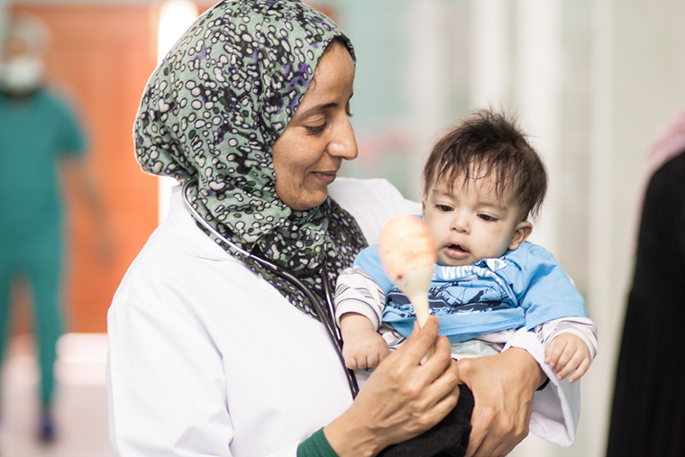Dr. Maryam calms a baby in hospital in Libya.
