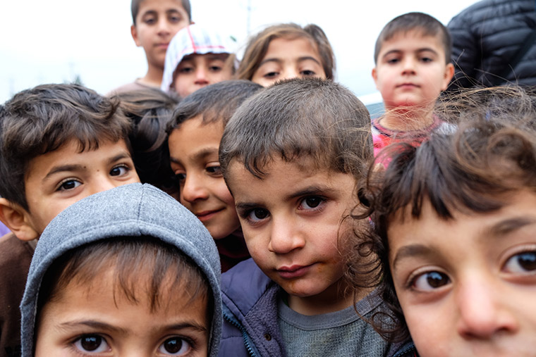 Displaced children in Iraq, Shabaks from Sinjar, gather under a grey sky.