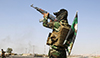 A fighter from the Shiite Badr Brigade militia wears a religious flag as he fires in the air at a checkpoint seized from Islamtic State militants outside the town of Amerli, Sept. 5, 2014.  Read more: http://www.al-monitor.com/pulse/originals/2015/01/iran-iraq-saraya-al-khorasani.html#ixzz3QP5Hvi6k
