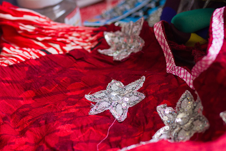 Adding hand-sewn embellishments to a hand-made dress.