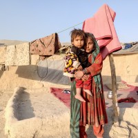 An older child holds a toddler in rural Afghanistan.