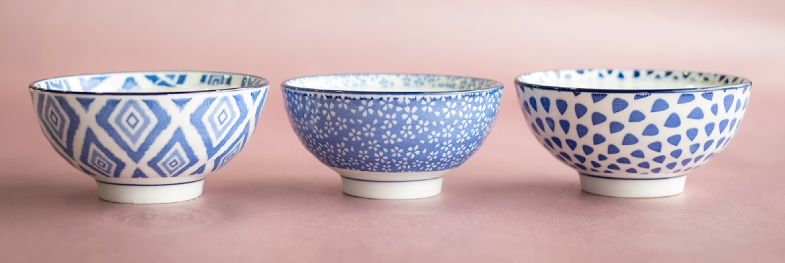 A row of three candles made in pretty, reusable blue-and-white bowls.