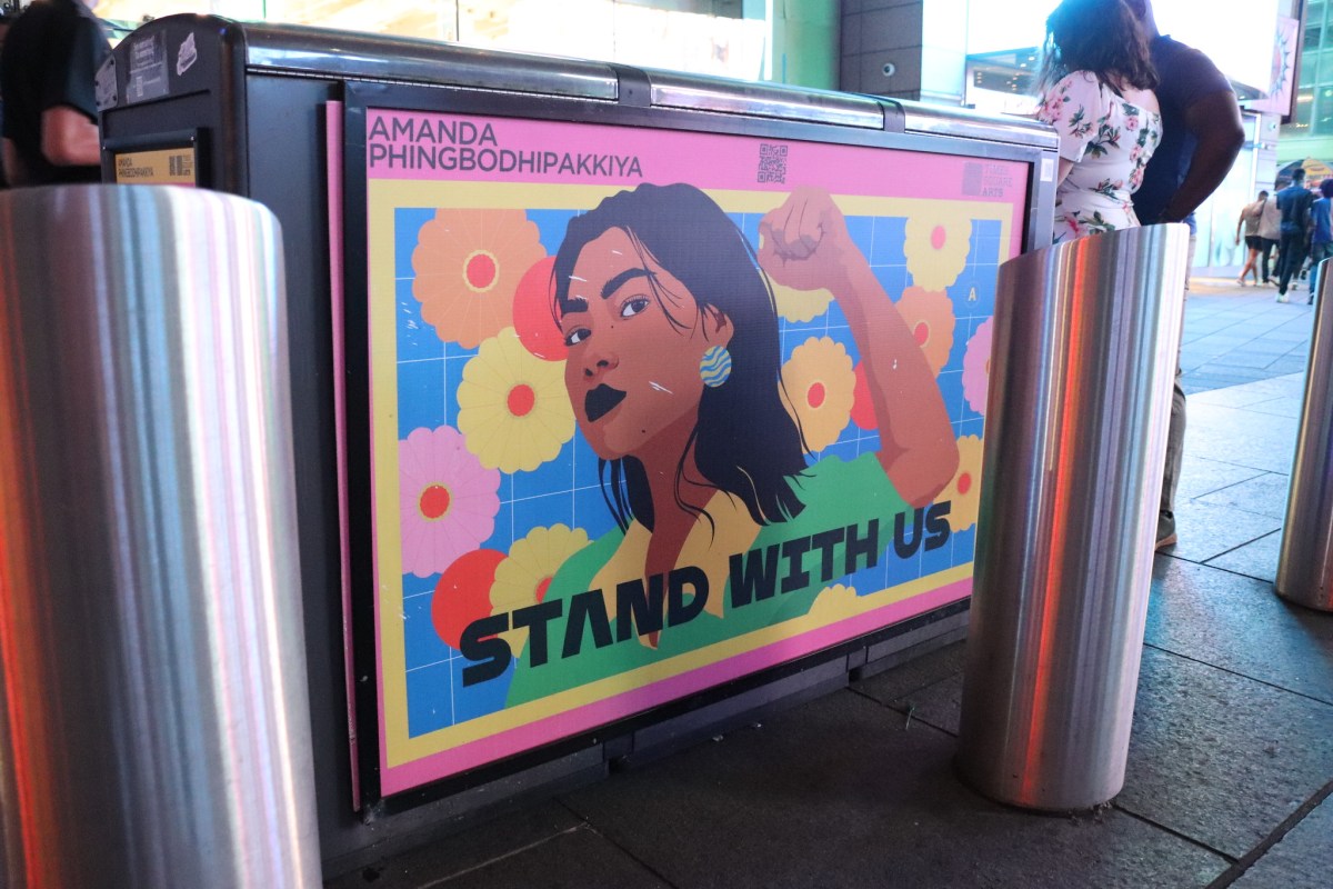 Brightly colored poster featuring the illustrated face of an AAPI woman, featuring the words "STAND WITH US"